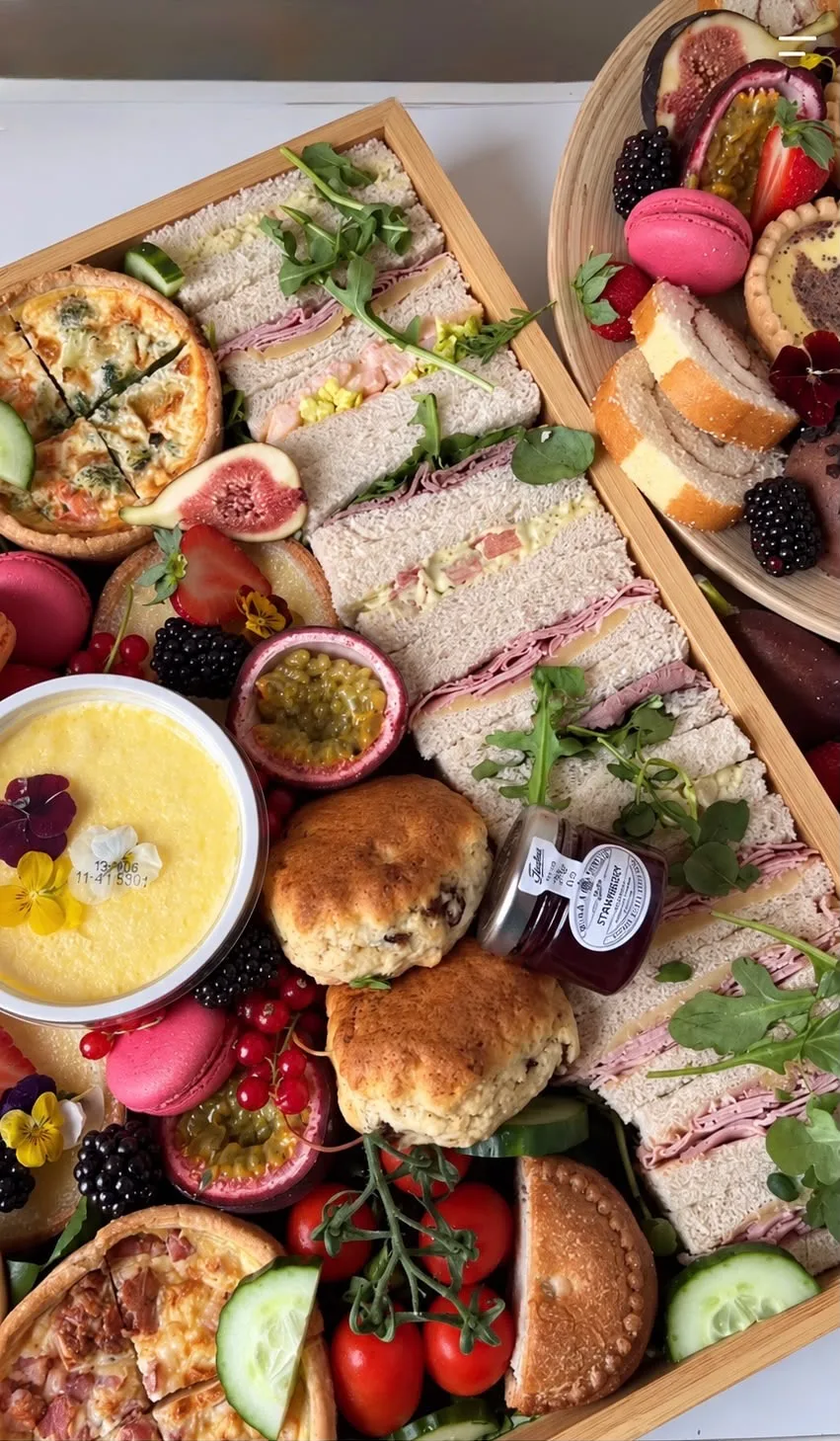 A cream tea box with finger sandwiches, scones, quiche and jam