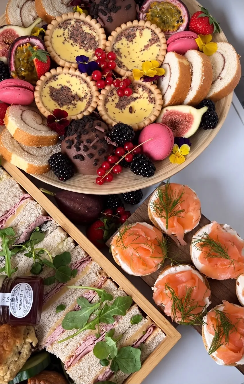 A sweet treats board with custard tarts, macarons and berries