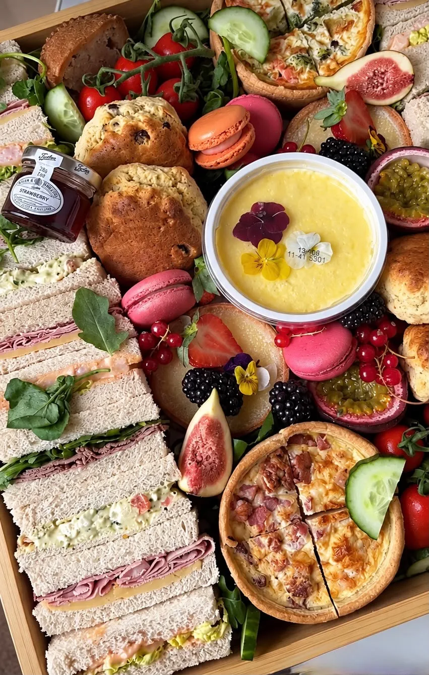 An afternoon tea box with finger sandwiches, scones, macarons and quiche