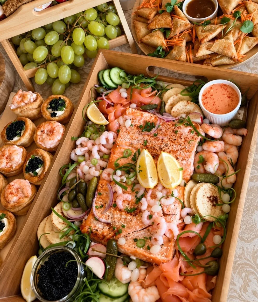 A seafood platter with salmon, prawns, blinis and garnishes